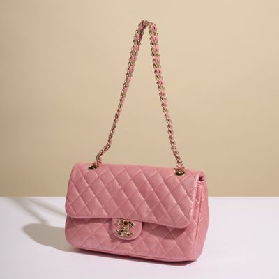 un sac Chanel rose posé sur une table blanche