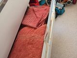 a white refrigerator in a small room with a red blanket in it