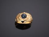 gros plan d'une bague en or avec une pierre bleue