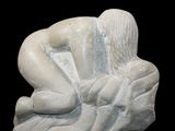 a white sculpture of a woman sitting on a rock