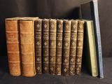 Plusieurs livres anciens sont alignés sur un fond noir.