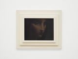 tableau représentant le visage d'une femme, dans un cadre blanc, accroché à un mur blanc