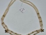 Collier de perles à deux rangs orné de breloques en forme d'étoile, sur fond blanc