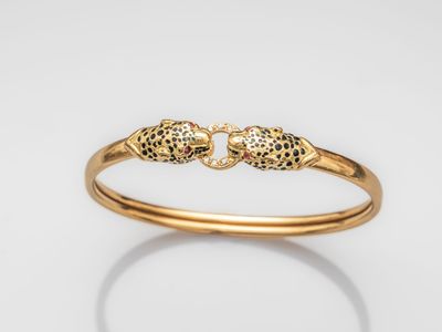 a gold bang bracelet with two skulls on it