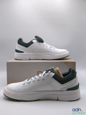 une paire de baskets blanches et vertes posées sur une boîte