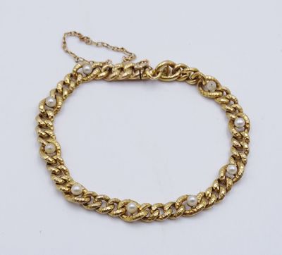 a gold chain bracelet with pearls on a white background