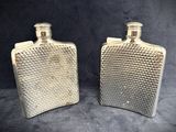 two silver flasks sitting on top of each other on a table