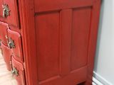 a red chest of drawers with a mirror on top of it