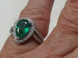 un gros plan sur la main d'une personne tenant une bague sertie d'une pierre verte