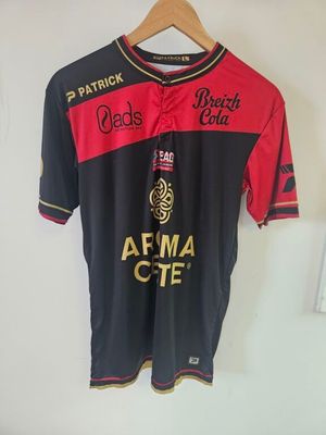 Le t-shirt est noir et rouge, et il y a une bouteille de bière imprimée dessus.