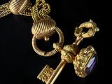 an image of a gold necklace with a key and a purple stone