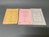 three books are lined up on a table in front of a gray background