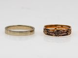 two gold and silver rings with diamonds on them on a white surface