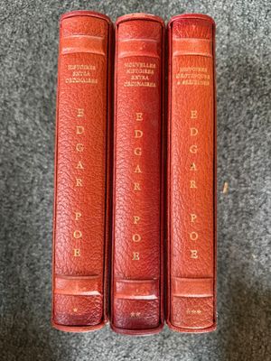 three red books sitting on top of each other on a carpet