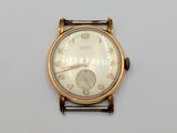 une montre-bracelet en or avec un cadran blanc sur une surface blanche