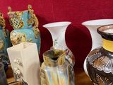 de nombreux vases posés sur une table, avec un mur rouge en arrière-plan