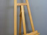 a wooden easel sitting on the floor next to a wall