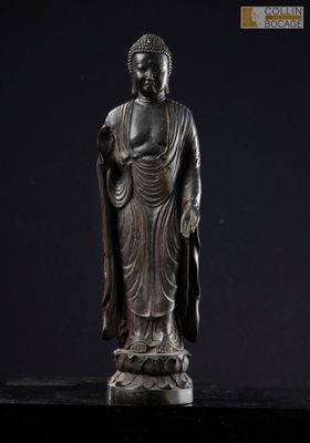 a bronze statue of a person standing on a black surface