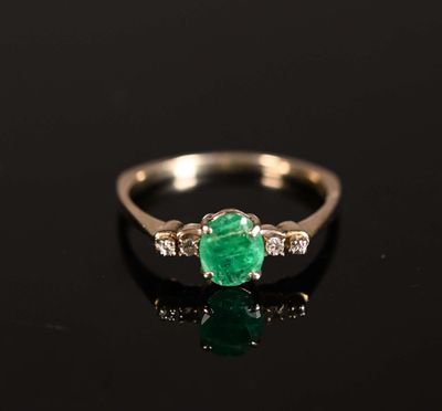 une bague en émeraude et diamant sur une surface noire