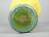 a green vase with a yellow ball in the background