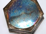 a silver plate with a blue glass in the middle of it