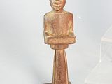 a small wooden statue of a man with his arms crossed