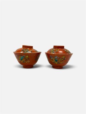 une paire de vases rouges ornés de motifs floraux sur fond blanc