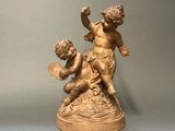 statue of a boy and a girl playing with a fan on a table