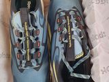 une paire de chaussures de course bleues et orange dans une boîte posée sur une table
