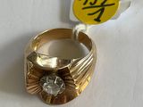 une bague en or sertie d'un diamant, posée sur une table blanche