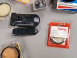 many items that are on a table that include a camera, a cell phone, and other items