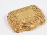 une boîte dorée posée sur une surface blanche, sur fond blanc