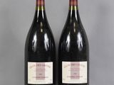 two bottles of red wine sitting on top of a glass table