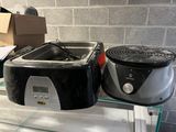 un mixeur noir et argenté et un mixeur noir et blanc posés sur une étagère en verre