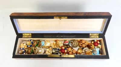 une boîte en bois remplie de bijoux variés, posée sur une surface blanche
