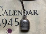 a bell hanging from a chain with a calendar in the background