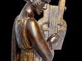 a bronze statue of a woman holding a musical instrument