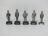 four silver statues of men in suits and hats on wooden bases