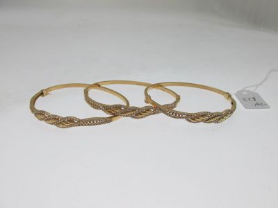 trois bracelets en or posés sur un fond blanc, avec une étiquette de prix