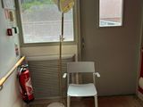 une chaise blanche dans un coin de la pièce, près d'une fenêtre