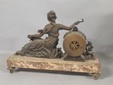 statue of a woman sitting on a stone base with a clock in her hand
