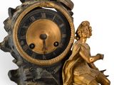 a gold clock with a statue of a woman sitting on top of it