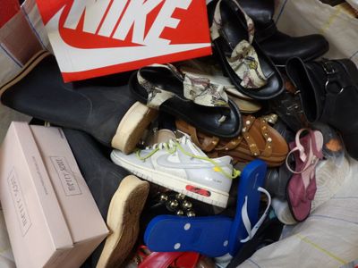 une pile de chaussures et des chaussures posées sur un lit