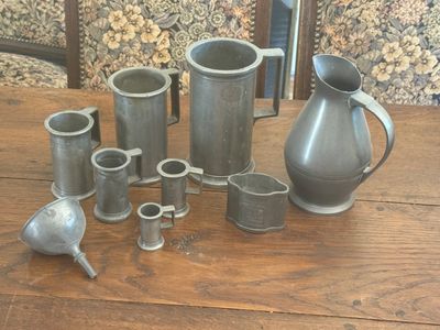 a lot of silver vases sitting on a wooden table