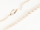 a close up of a necklace with pearls on a white surface