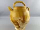 a yellow vase with a handle sitting on a table