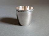 a silver cup with a beaded rim on a table
