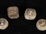 quatre petits objets argentés sont posés sur une surface noire