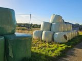 many bales of hay on the side of the road
