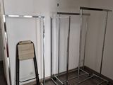 a picture of a room with a rack of clothes and a chair
